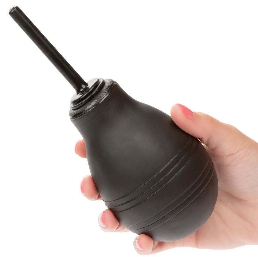 A hand holding a black rubber bulb douche against a clean white background.